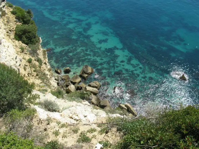A group of people standing on top of a cliff next to the ocean